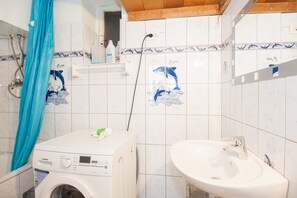 Ein Badezimmer mit Waschmaschine, Waschbecken und Duschvorhang.