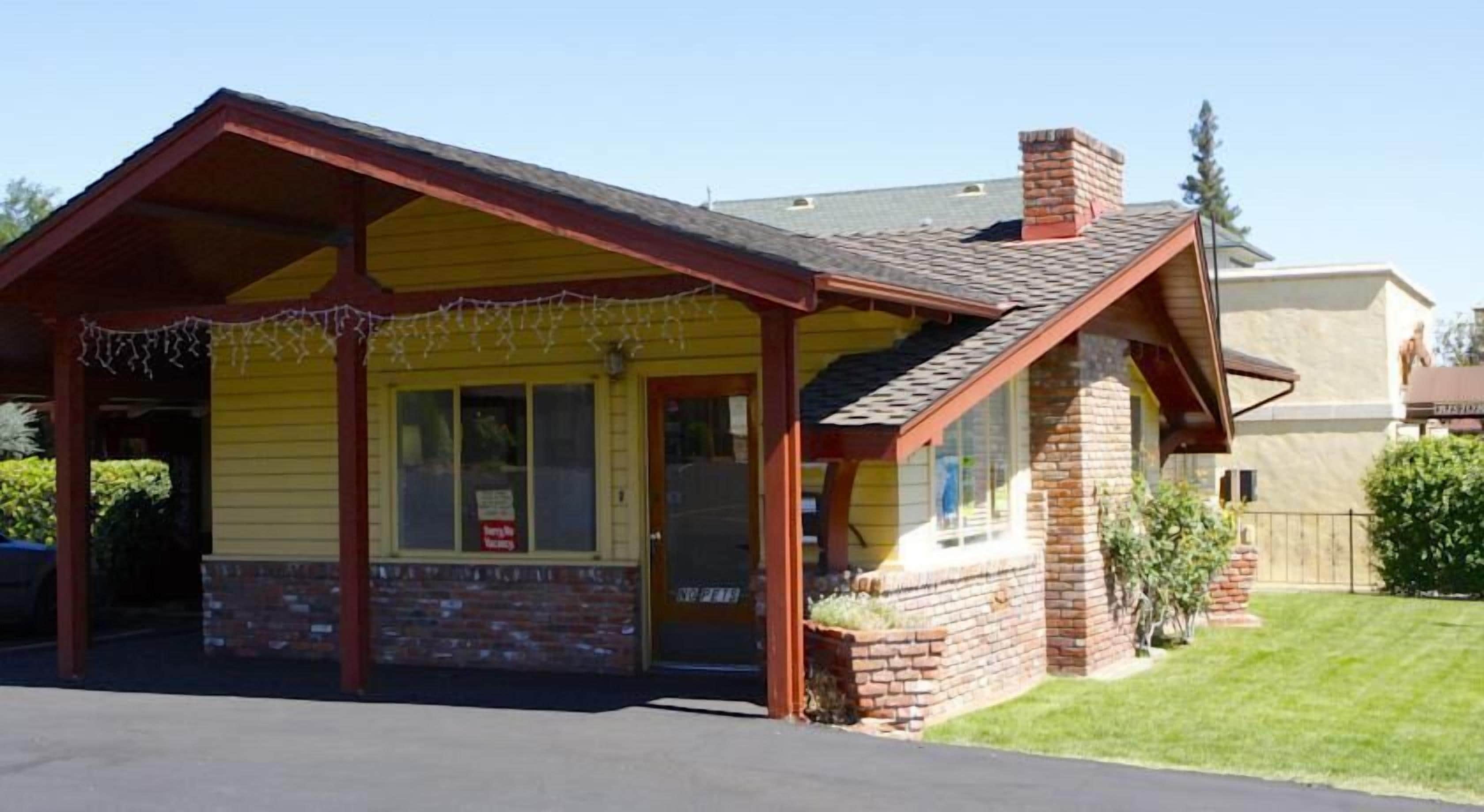 A small, yellow building with a brick chimney, a covered porch, and a 'For Rent' sign.