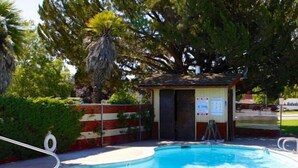 Une piscine avec un petit poste de surveillance pour les sauveteurs et une zone délimitée par une clôture.