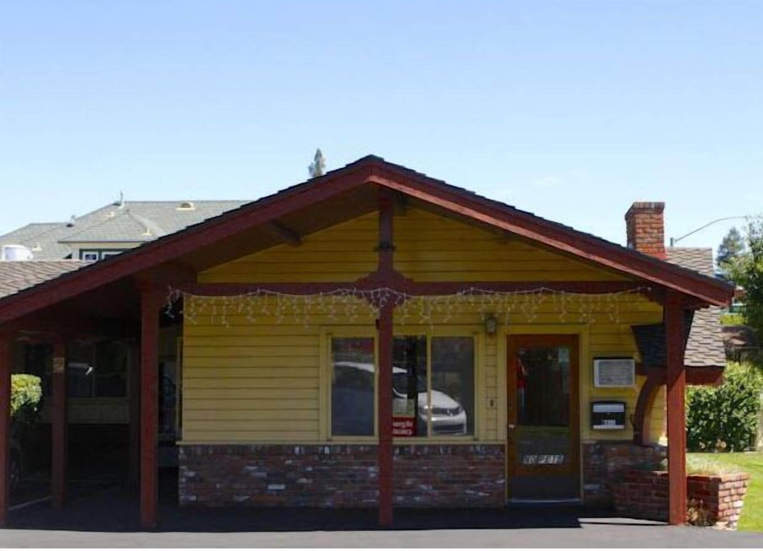 A yellow building with a red roof and a covered porch.