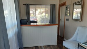 Une pièce avec un plancher en bois, un radiateur blanc, une chaise bleue et une fenêtre avec des rideaux gris.