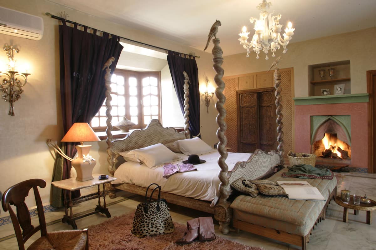 Um quarto tradicional com uma cama de dossel, lareira e um candelabro.