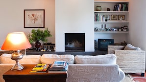 Una sala de estar con chimenea, sofá, sillón y estantería.
