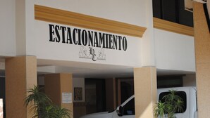 Ein Hotel Eingang mit einem Schild, auf dem 'ESTACIONAMIENTO' steht, und einem weißen Fahrzeug, das darauf parkt.