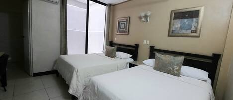 A hotel room with two single beds, a sliding door, a wall-mounted air conditioner, and a framed picture.