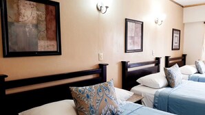 Ein Hotelzimmer mit zwei Betten, jeweils mit Kopfstütze, einem großen abstrakten Gemälde an der Wand und einem gerahmten Bild über den Betten.