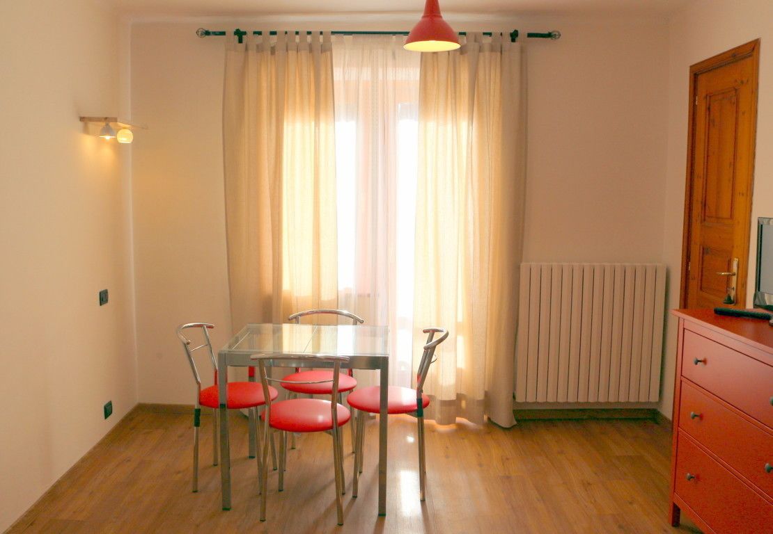 A dining area with a table and four chairs, a radiator, and a wooden cabinet.
