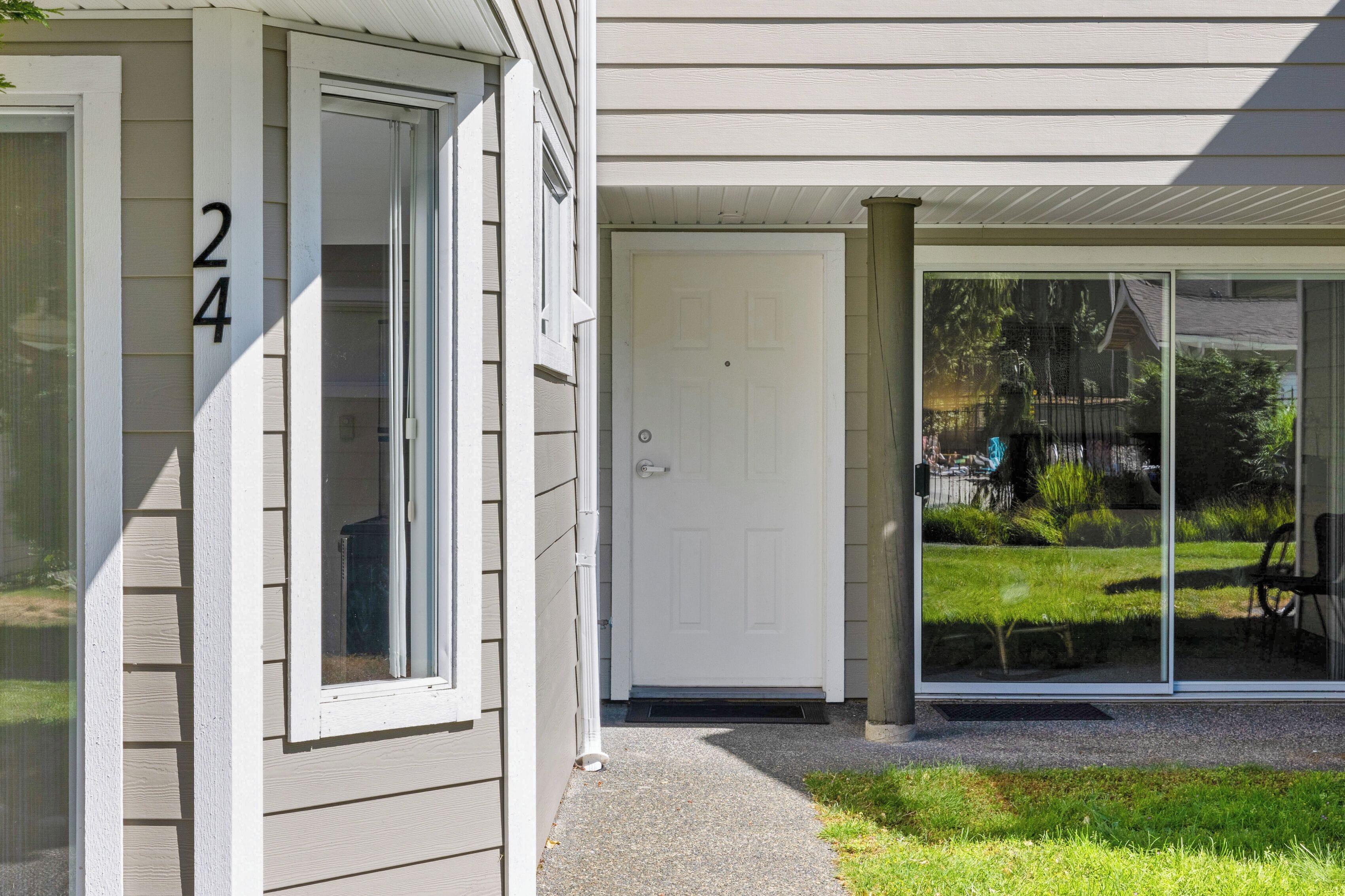 A house with a white door, a number '24' on the side, and a glass door leading to a covered porch.