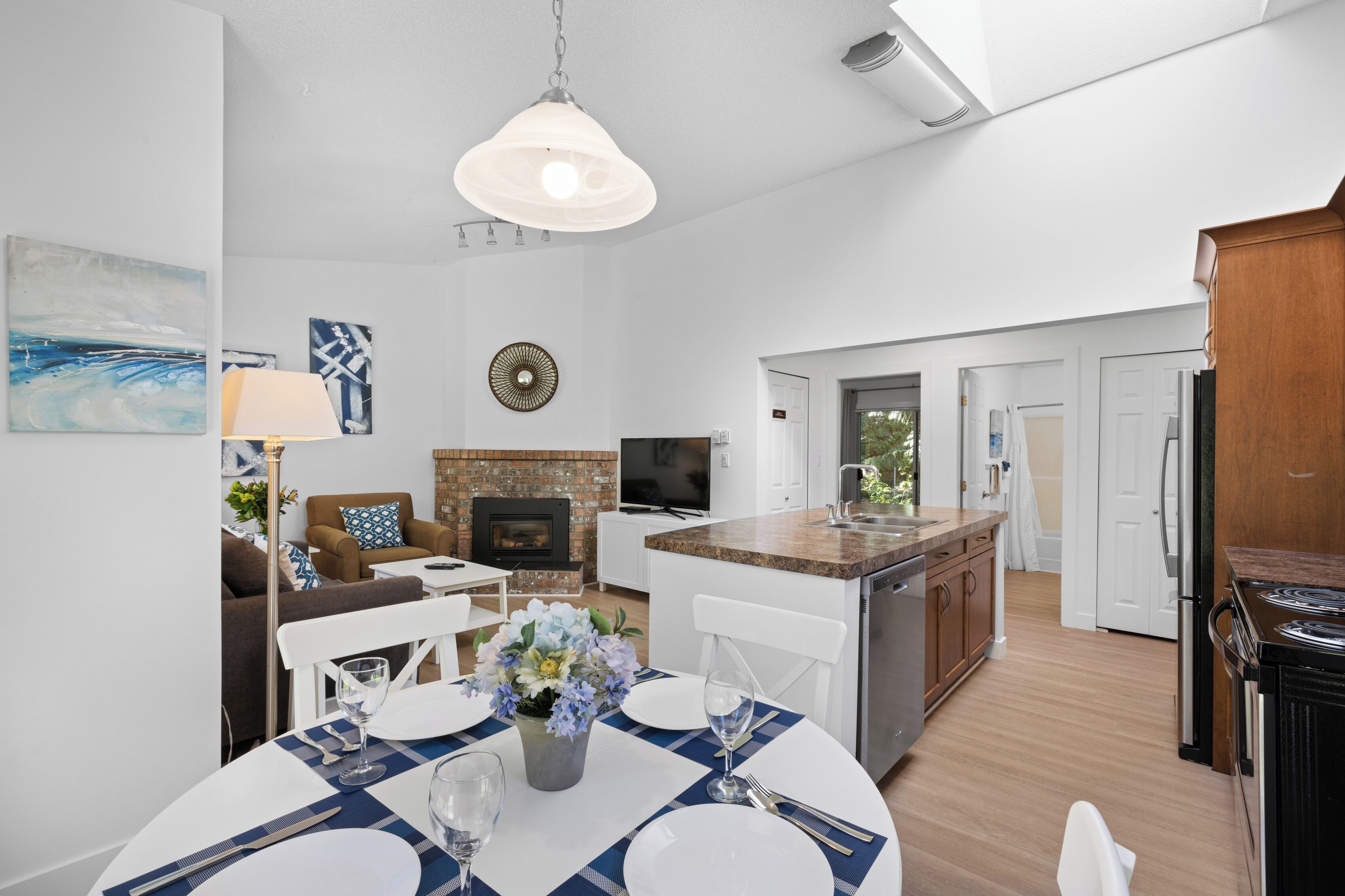 A modern kitchen with a central island, white cabinetry, and a built-in oven.