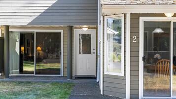 A house with a sliding glass door entrance, a number '2' on the door, and a visible outdoor seating area with a table and chairs.
