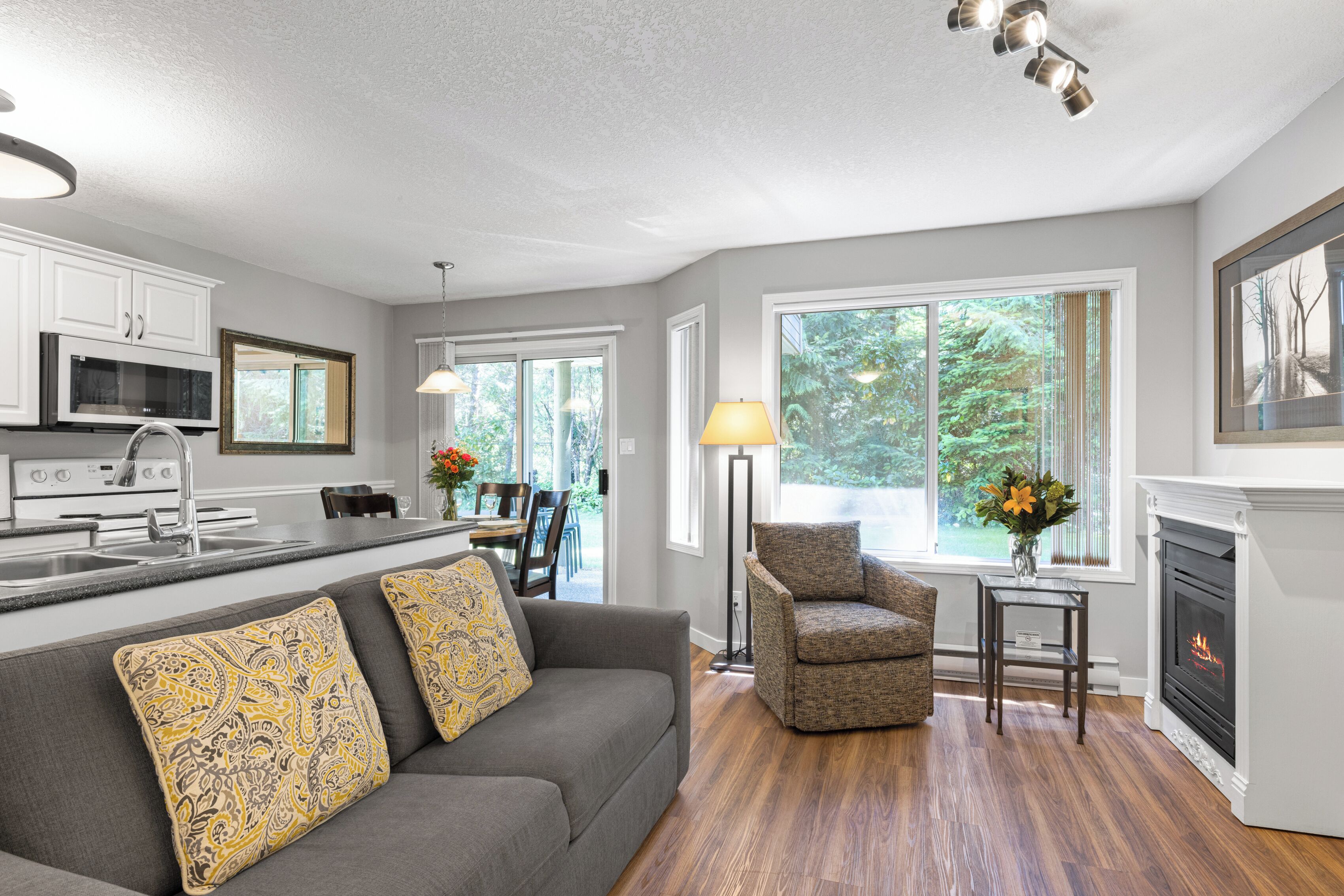 A modern kitchen with white cabinets, a microwave, and a dining area with a table and chairs.