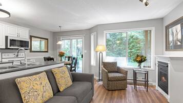 A modern kitchen with white cabinets, a microwave, and a dining area with a table and chairs.