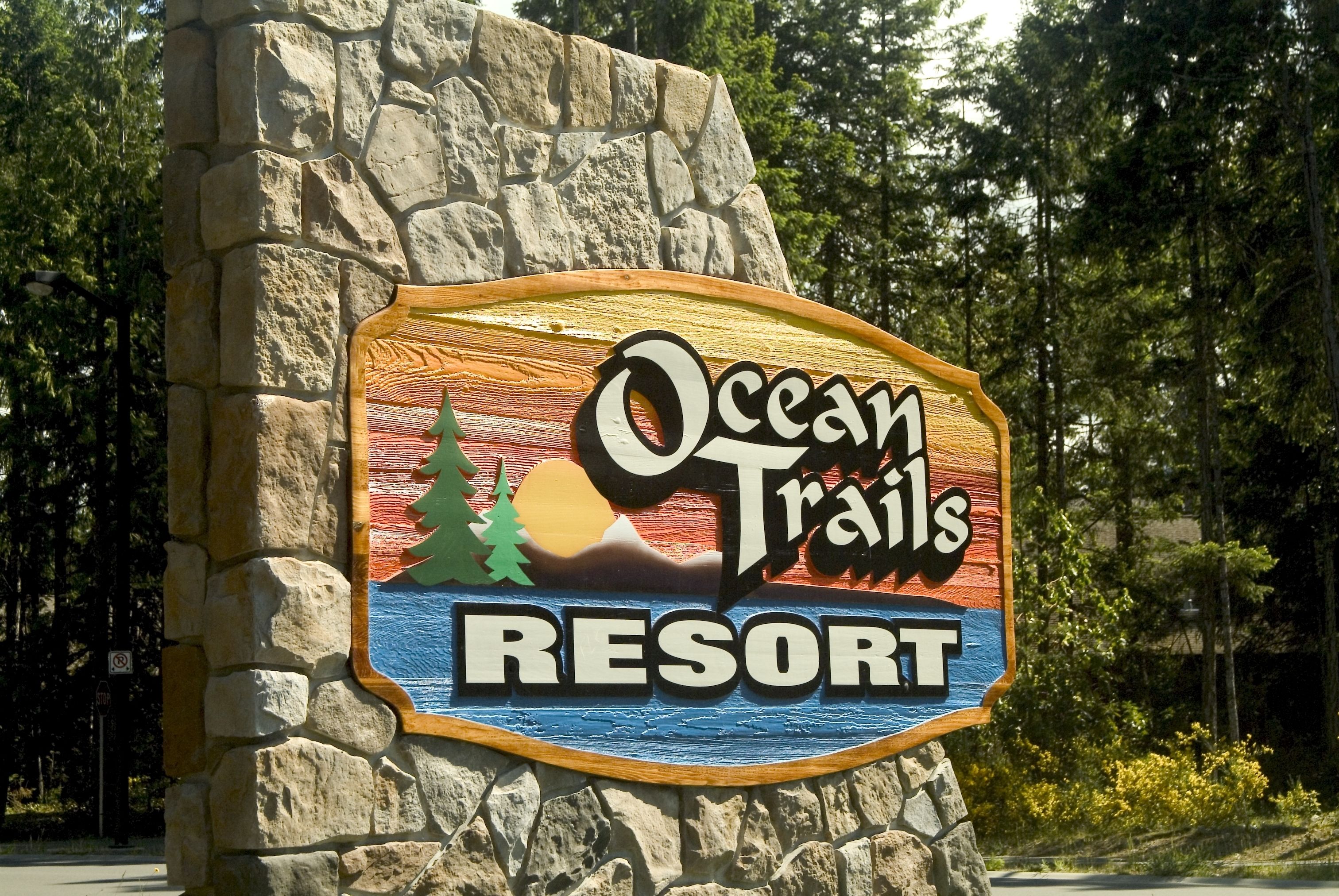 A sign for Ocean Trails Resort with a scenic design.