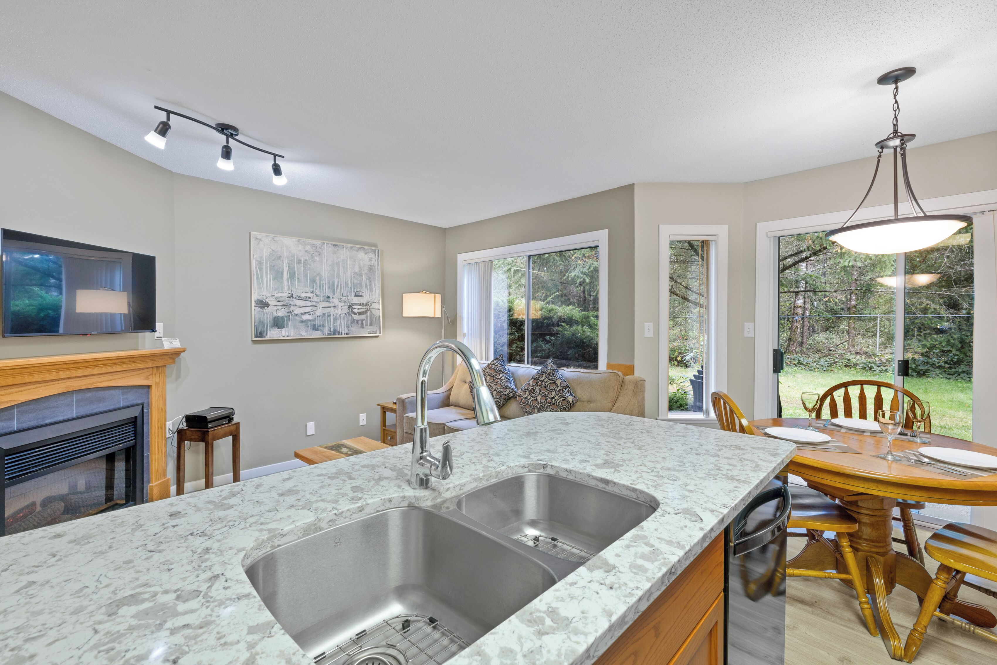 A kitchen with a large island, double sink, and dining area with chairs and a table.