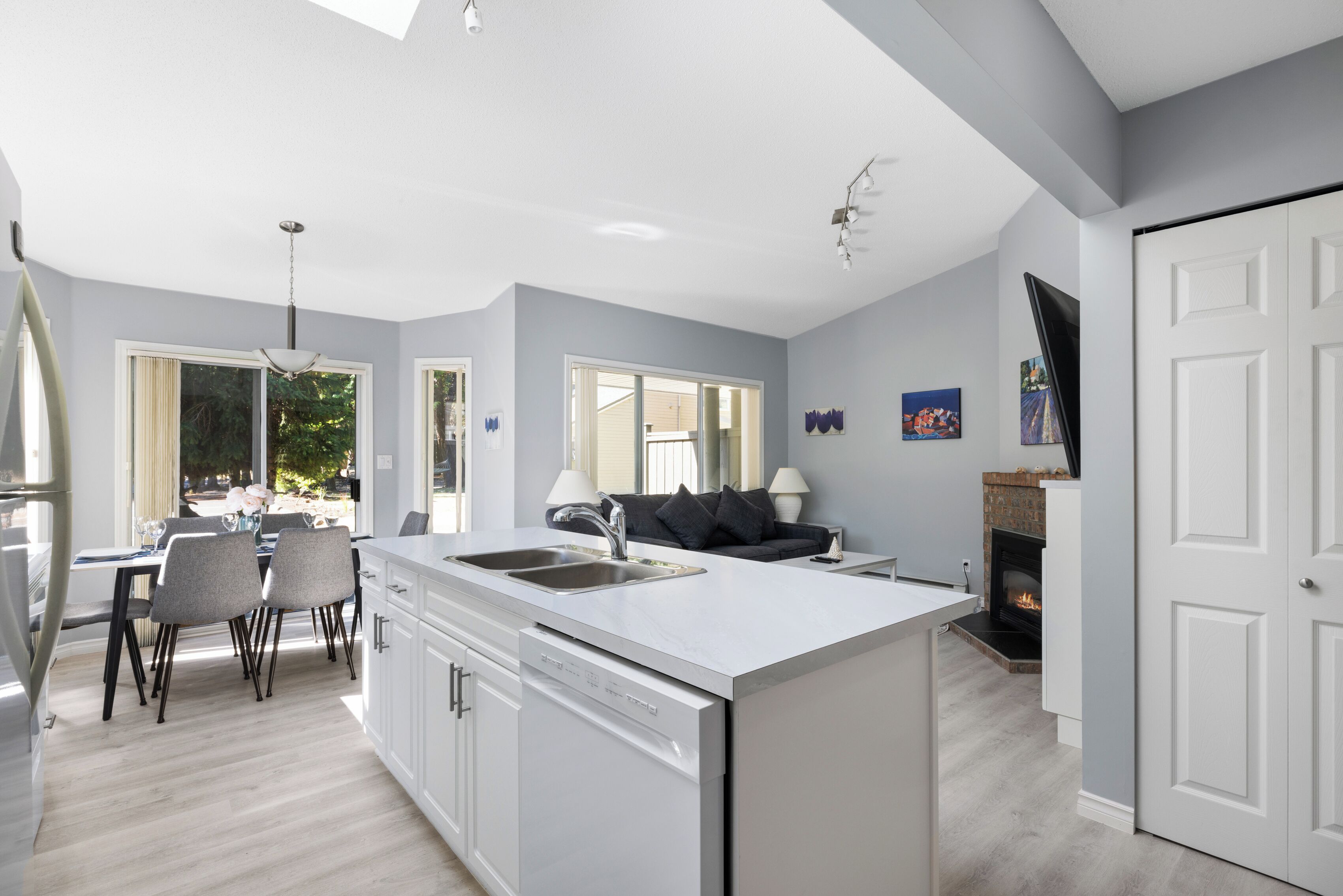 A modern kitchen with a central island, a dining area with chairs, and a sofa.