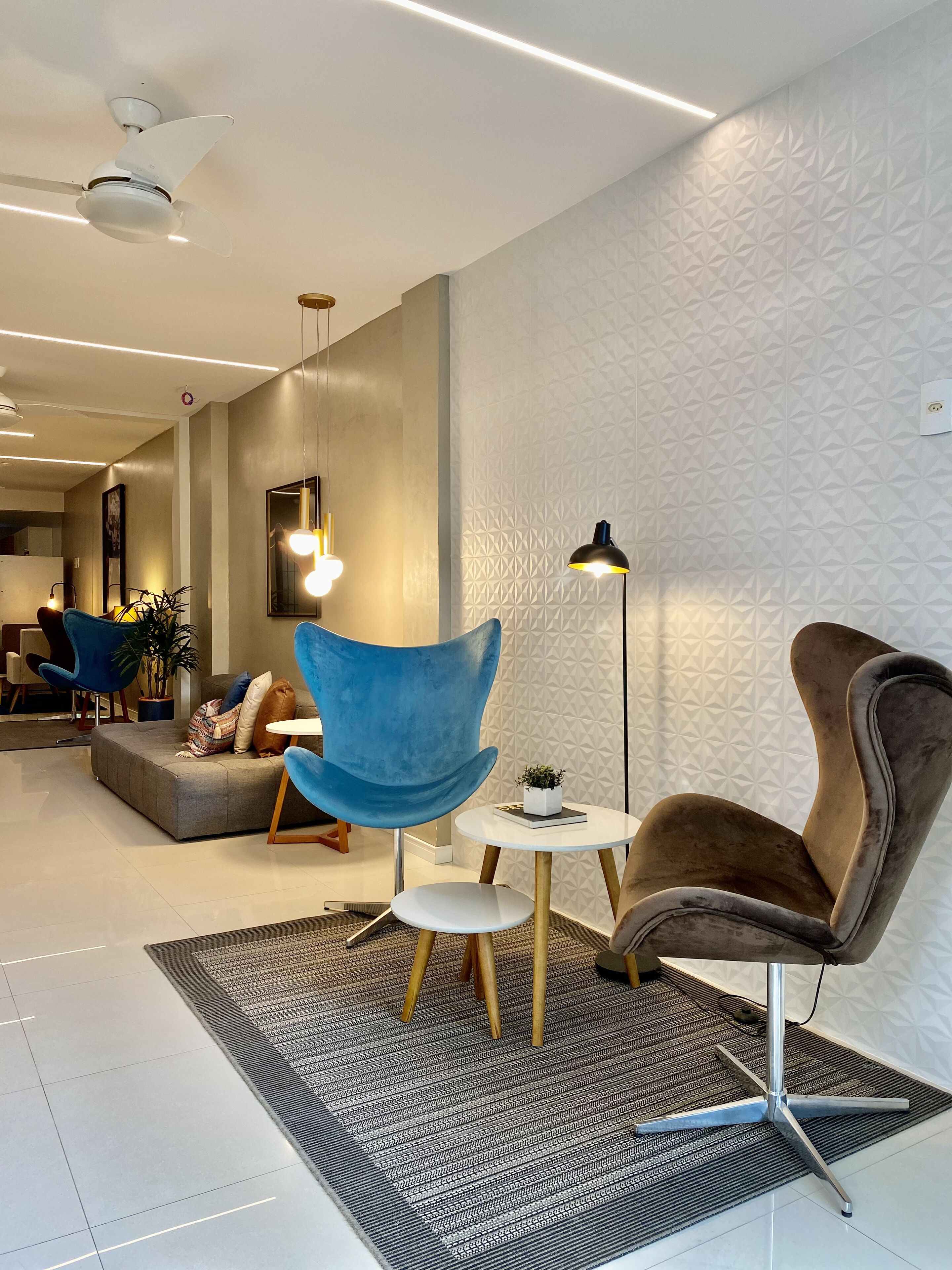 A modern living room with a sofa, blue armchair, and brown armchair, a small round table, and a patterned rug.