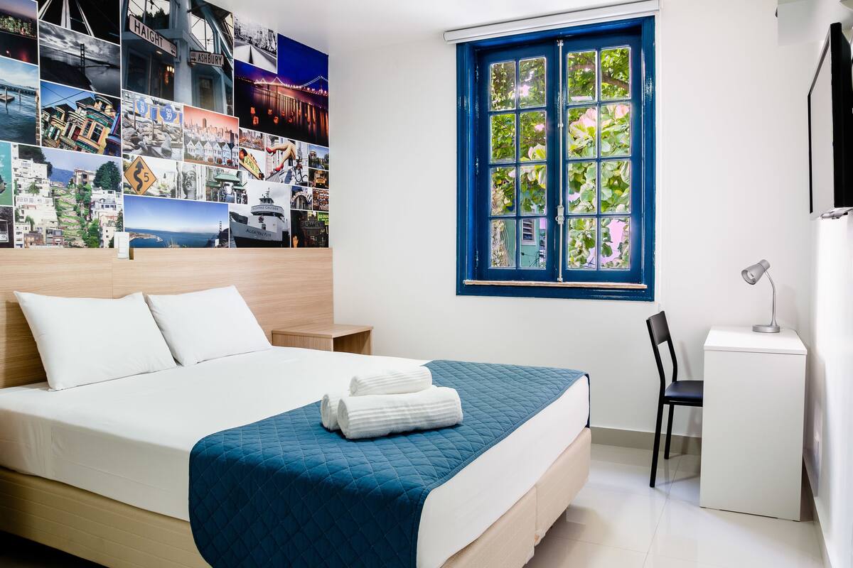 A neatly arranged bedroom with a bed, a desk, and a chair.