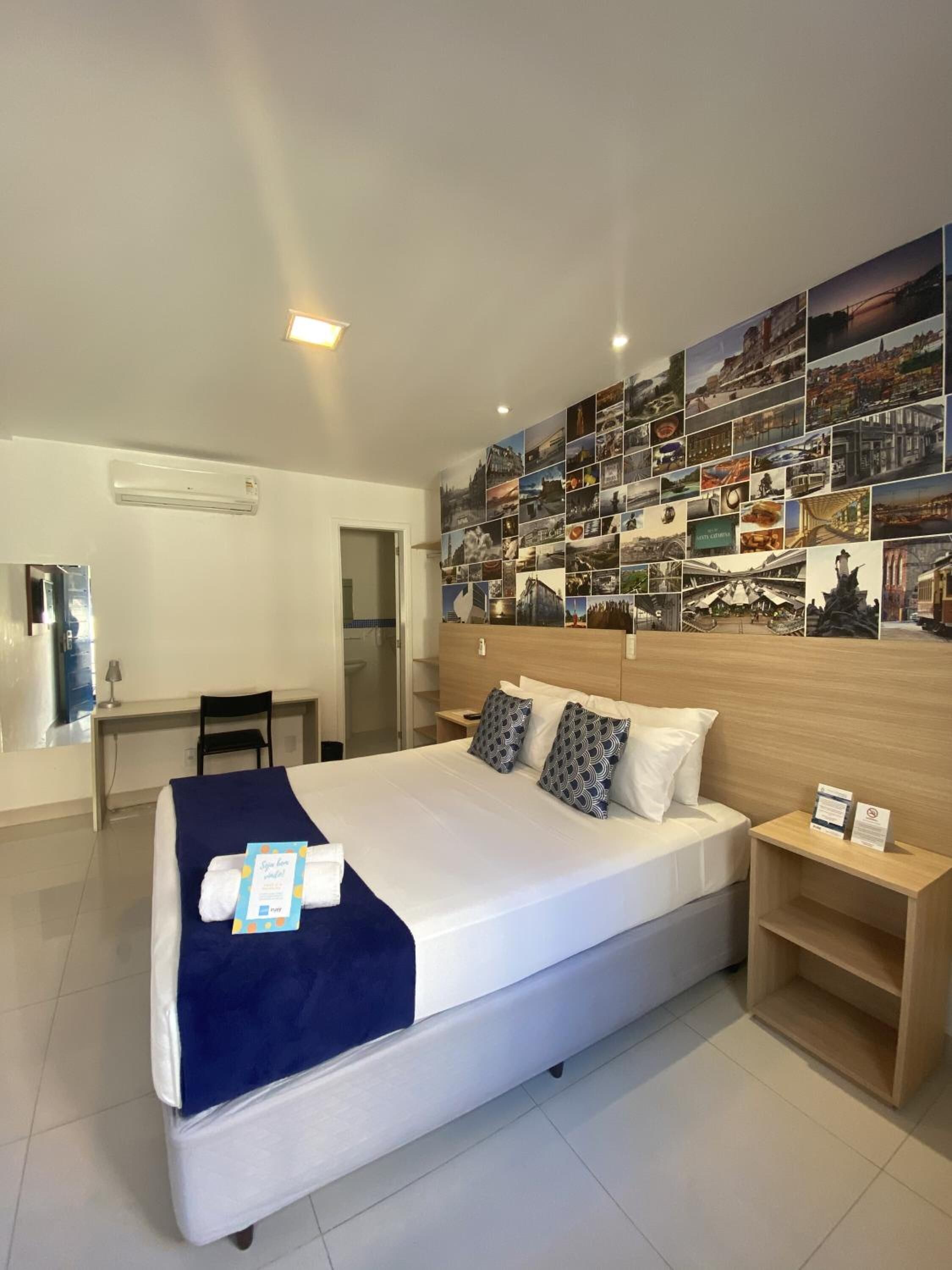 Une chambre d’hôtel avec un grand lit, un bureau et un mur décoré de photos.