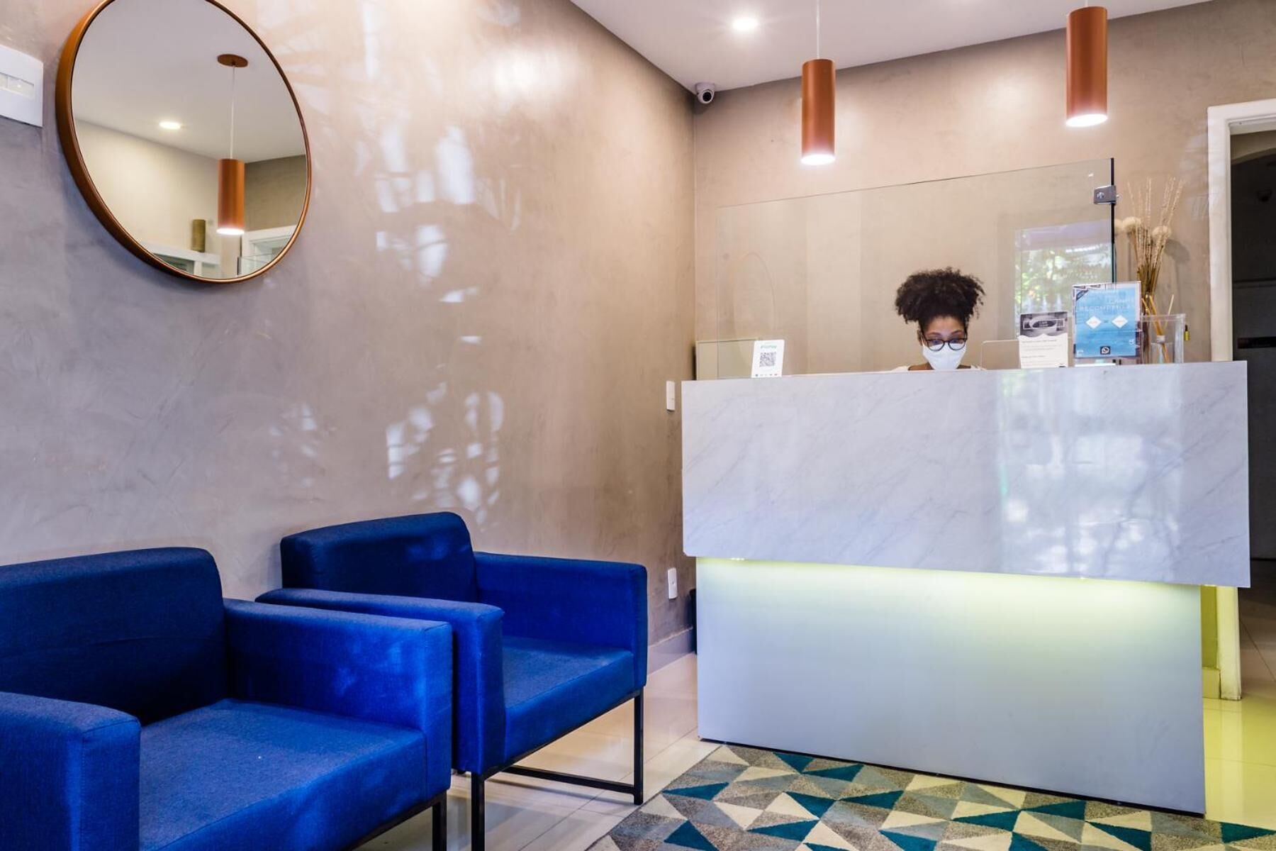 A reception area with a marble counter, blue seating, and a geometric patterned floor.