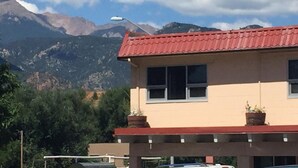 Un edificio con techo rojo, ventanas y plantas en macetas en el balcón.