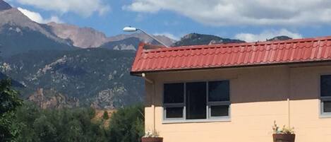 Un edificio con techo rojo, ventanas y plantas en macetas en el balcón.