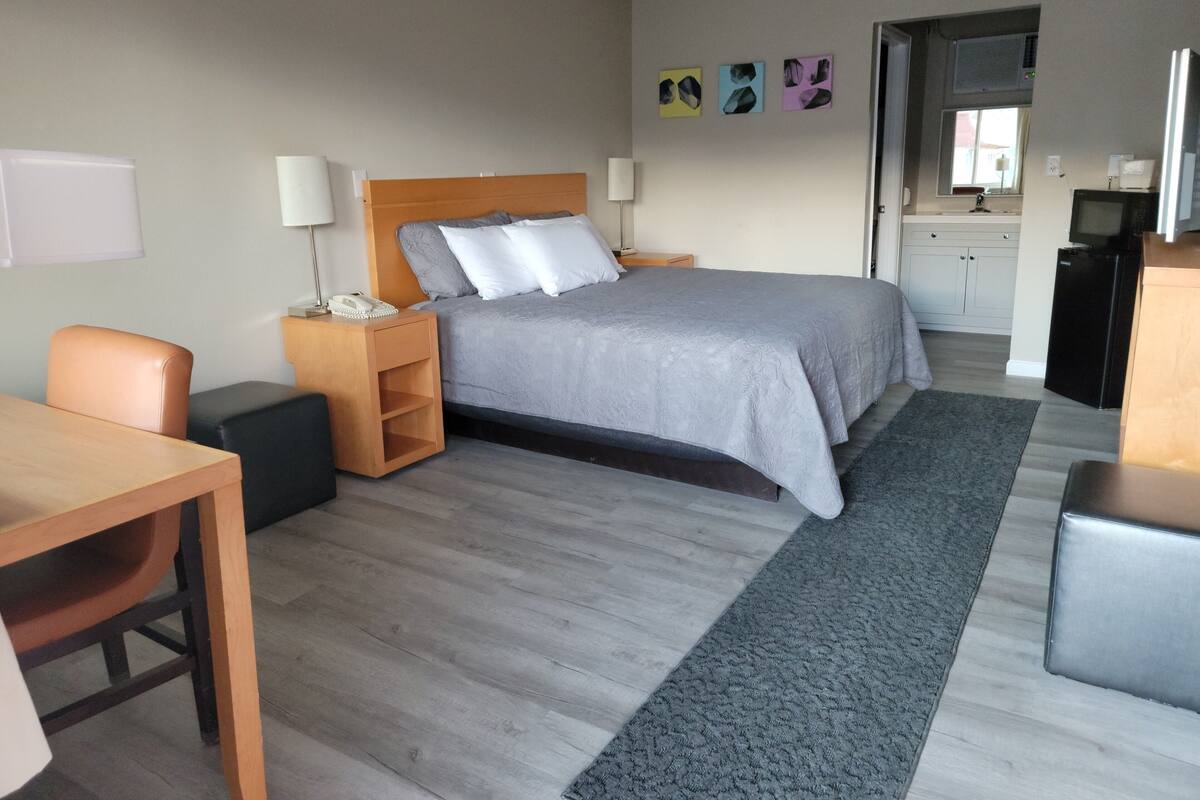 Une chambre d’hôtel comprenant un lit, des tables de chevet, un bureau et une kitchenette.