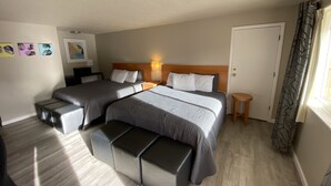 Habitación de hotel con dos camas, una mesita, un banco y una puerta.