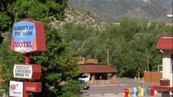 Letrero de motel con una placa que dice 'Garden of the Gods', un letrero de bienvenida y un sello de aprobación rojo.