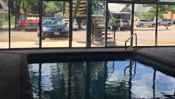 Piscina con vistas a coches aparcados y edificios.
