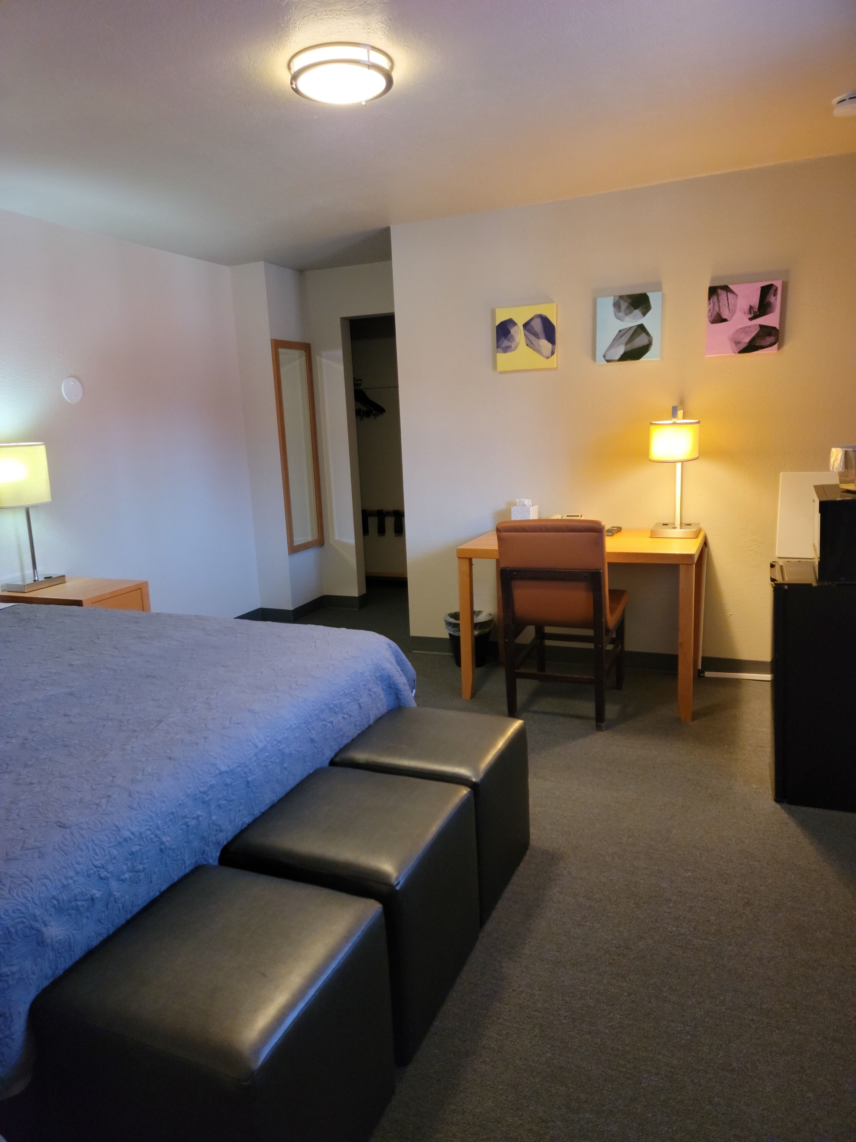 Hotellihuone, jossa on sänky, työpöytä, tuoli ja lamppu.