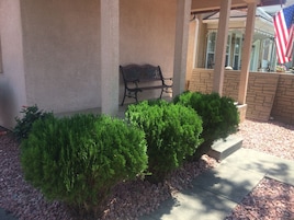 Un patio con pared de piedra, un banco y una pequeña bandera estadounidense.