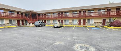 A motel with a two-story structure, a parking lot with marked handicapped spaces, and a staircase leading to the upper level.
