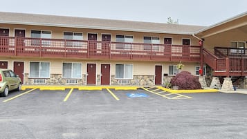 A motel with a two-story structure, a parking lot with handicapped accessibility, and a staircase leading to the upper level.