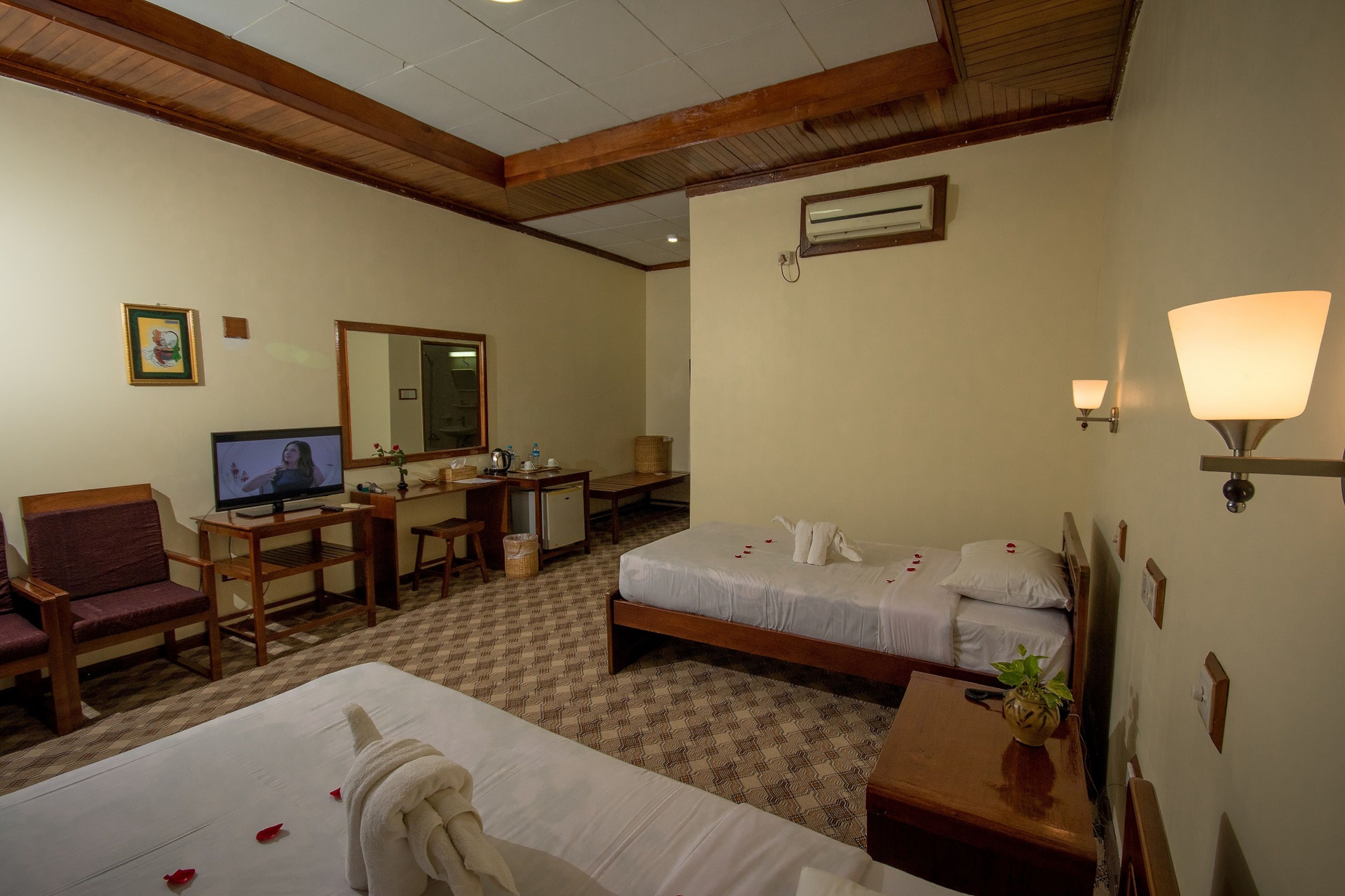 Habitación de hotel con dos camas, un escritorio, un televisor, un espejo y una lámpara.