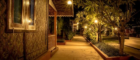 Un sendero que conduce a un edificio con un muro exterior decorativo y un vestíbulo cubierto.