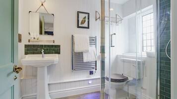 Un baño con lavamanos pedestal, cabina de ducha de vidrio y inodoro con función bidé.