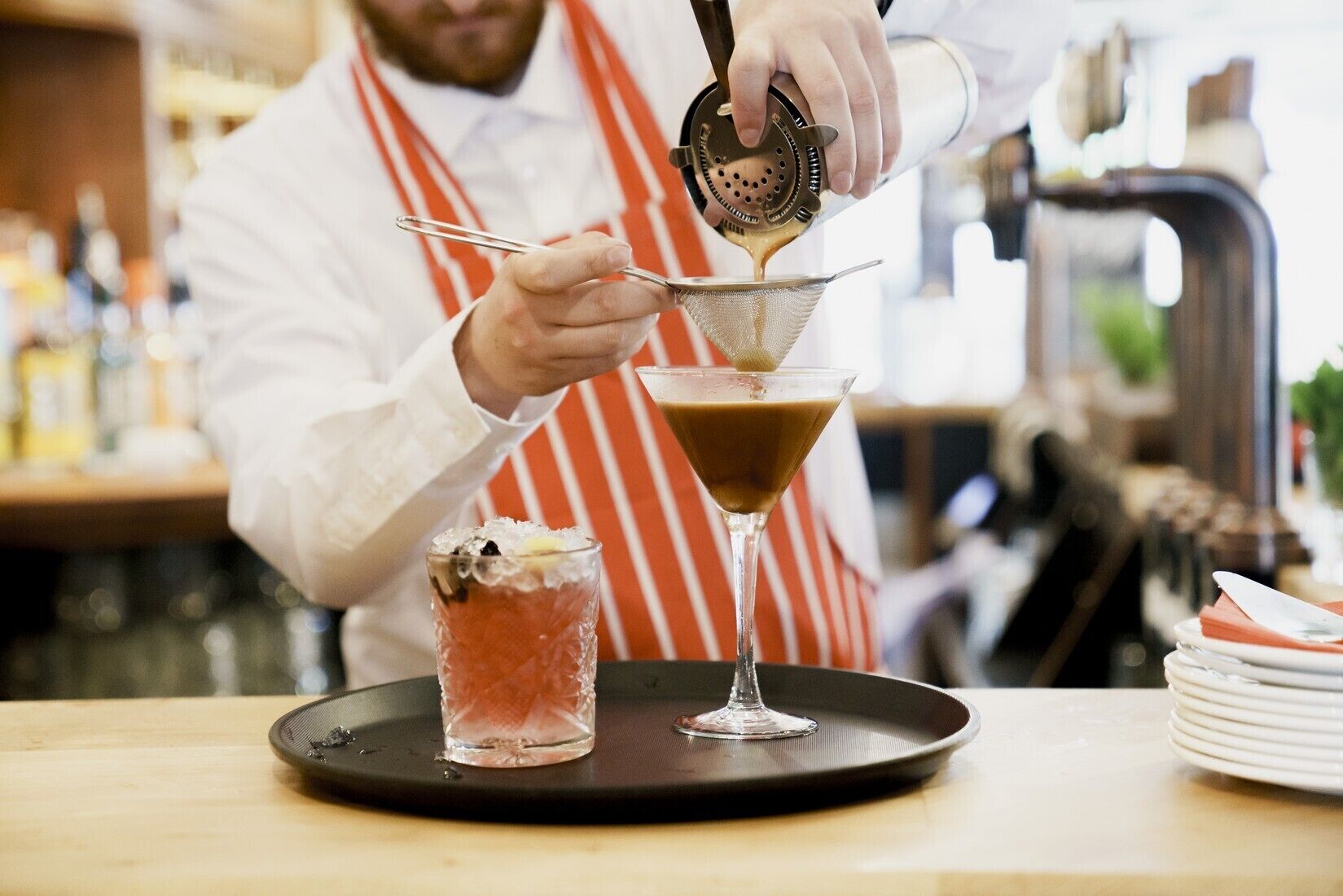 A bartender preparing a cocktail in a martini glass.