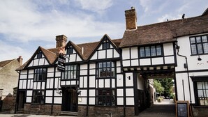 Un edificio tradicional de estilo Tudor con fachada blanca y negra, un letrero que dice “The Red Lion” y una entrada visible.