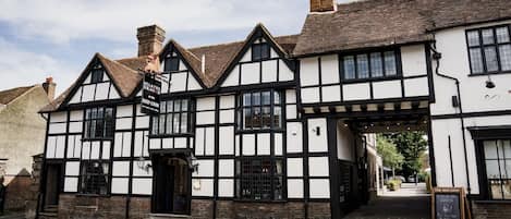 A traditional Tudor-style building with a black and white facade, a sign reading "The Red Lion," and a visible entrance.