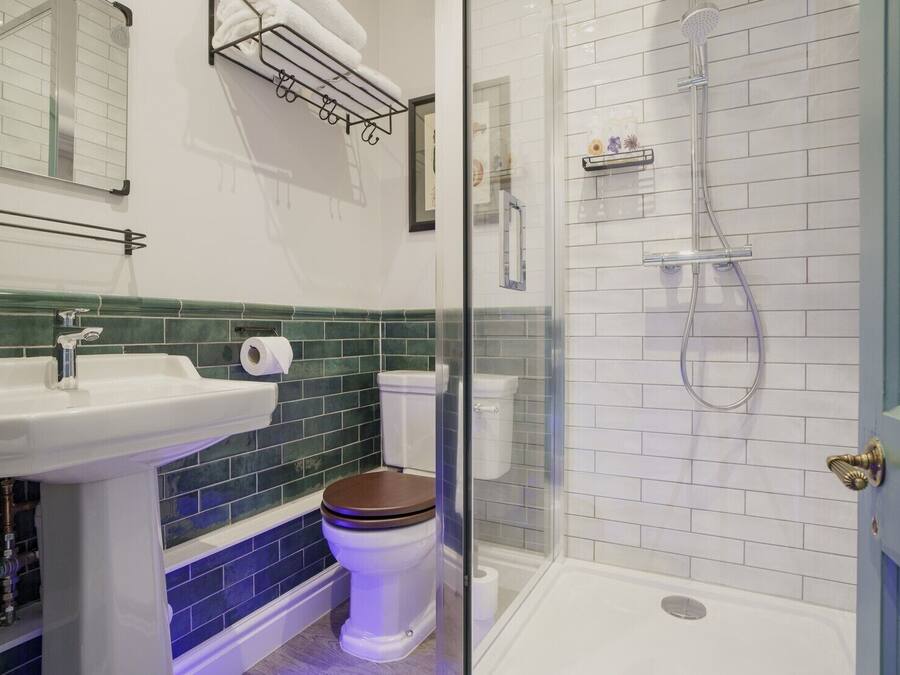 Une salle de bain avec un lavabo blanc, des toilettes et une douche, le tout dans un espace de douche délimité par des parois en verre.
