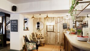 Un área de bar acogedora con paredes de madera, una barra con dispensador de vino y dos sillones tapizados.