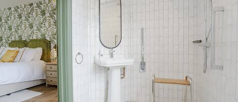 A modern bathroom with white tiles, a white sink, a mirror, and a shower.