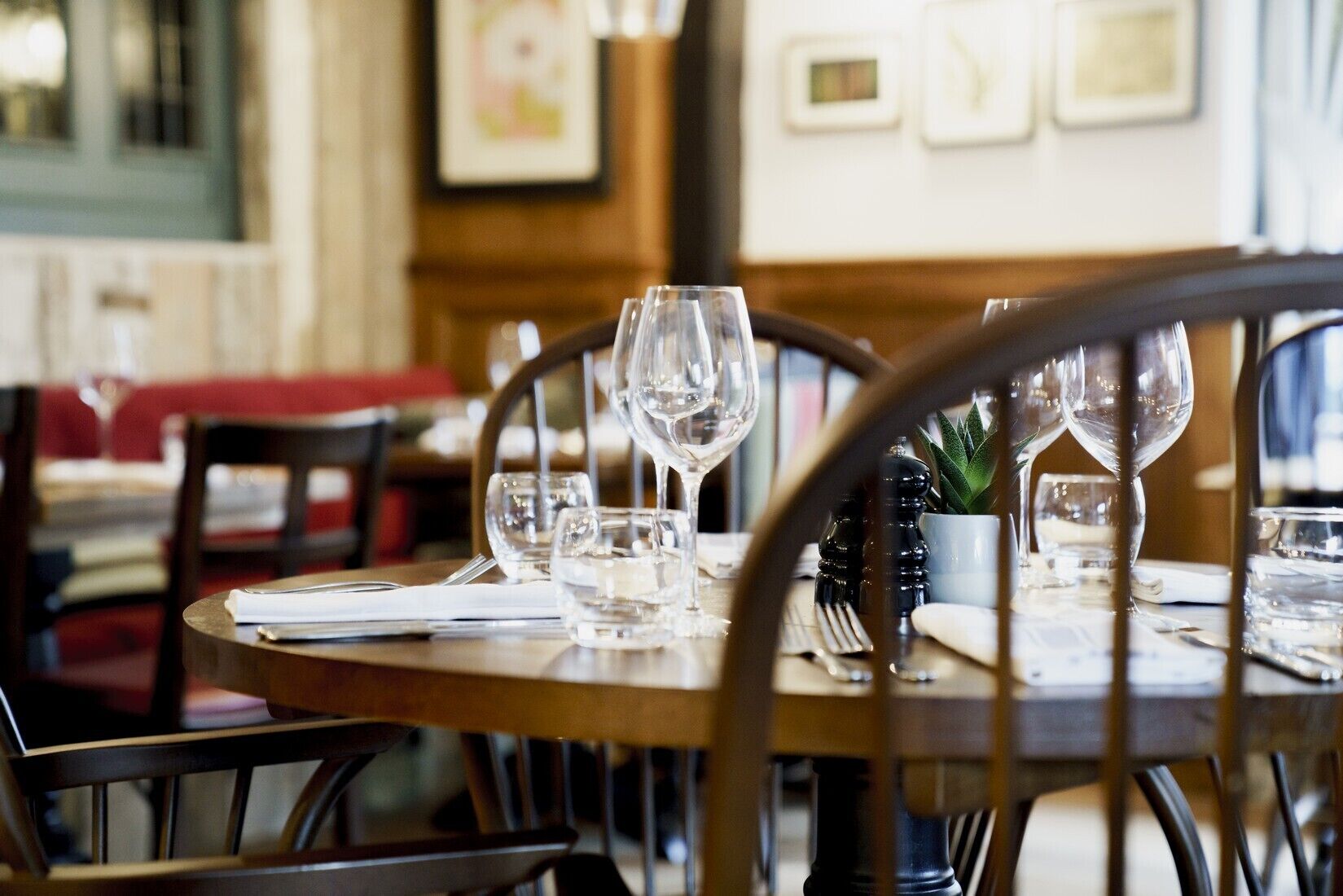A restaurant table set with clear glassware and a small potted plant.