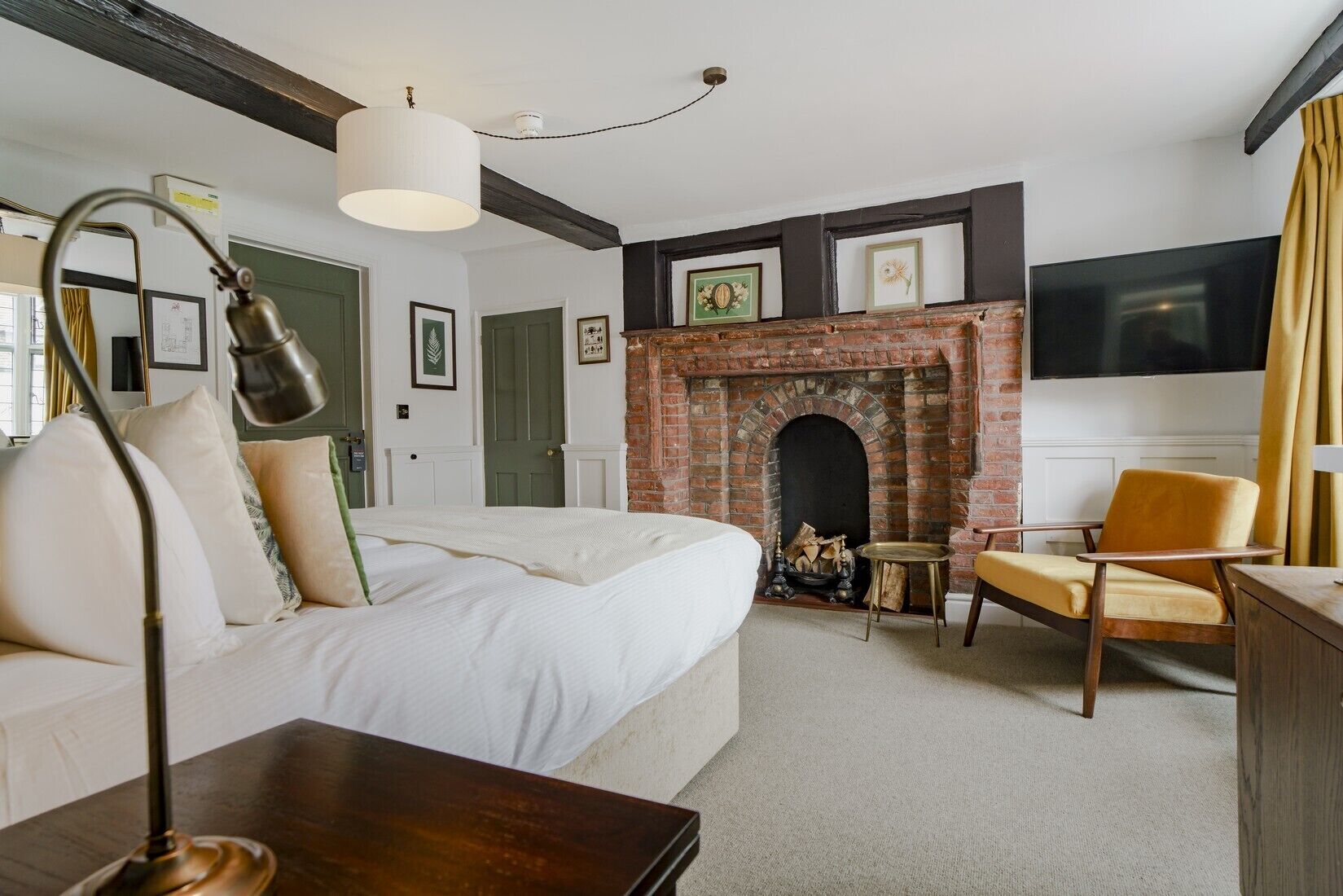 A bedroom with a brick fireplace, a bed, a desk, and a chair.