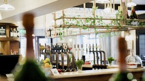 Una zona de bar con varias griferías de cerveza, una vitrina de cristal y un mostrador con la carta.