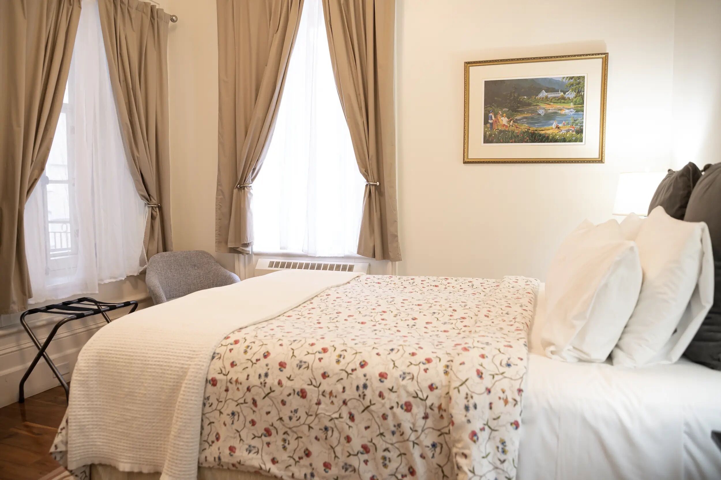 Un dormitorio con cama, una silla, un radiador y un cuadro en la pared.