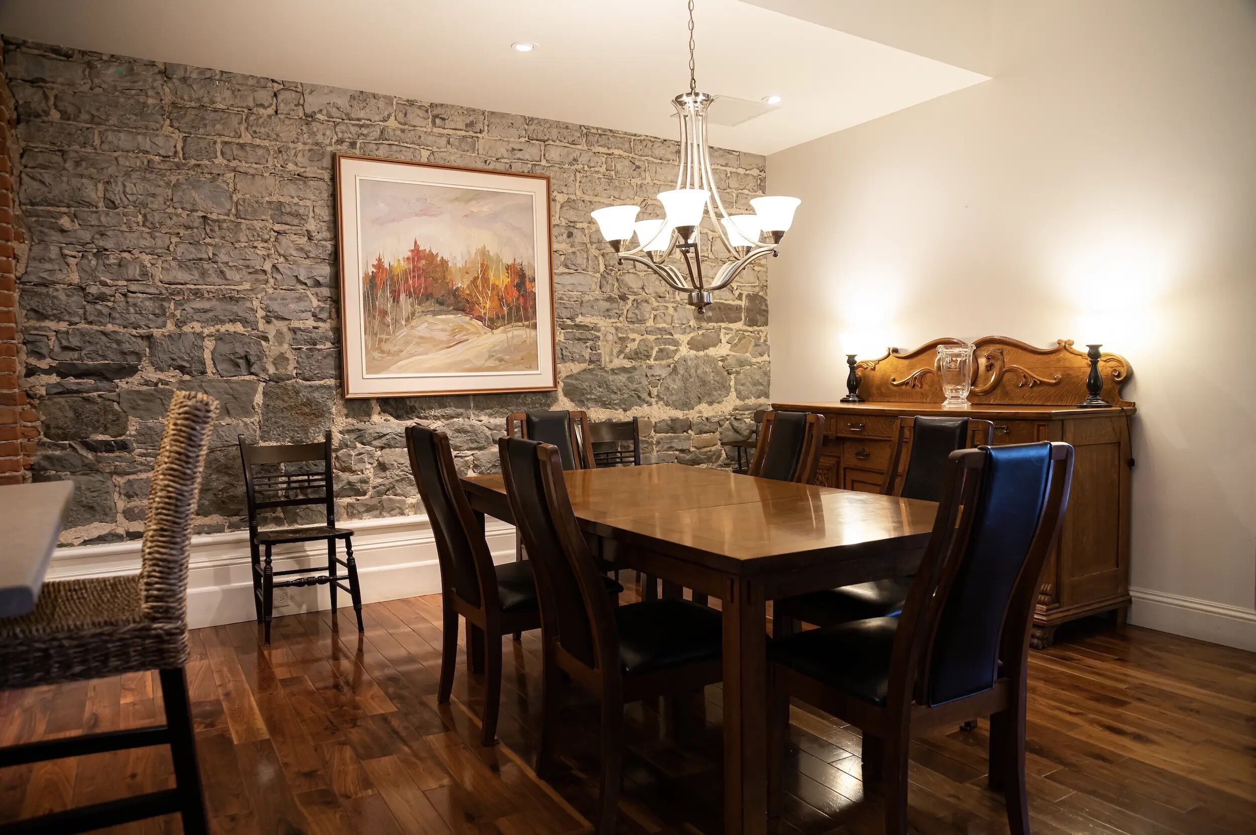 A dining room with a stone wall, wooden table, and chairs.