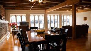 A dining area with a wooden table and chairs, large windows with a city view, and a chandelier. - Royal Dalhousie Condos (Québec City)