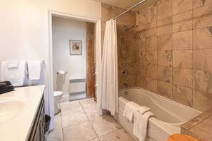 Een badkamer met een bad, douche, toilet en wastafel.