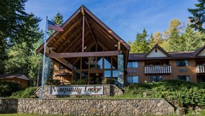 A lodge with a prominent wooden pavilion, stone walls, and a sign reading "Nisqually Lodge". - Nisqually Lodge (Ashford)